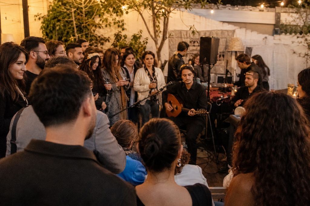 Young and older Armenian guests gathered around a live acoustic performance in a Los Angeles courtyard.