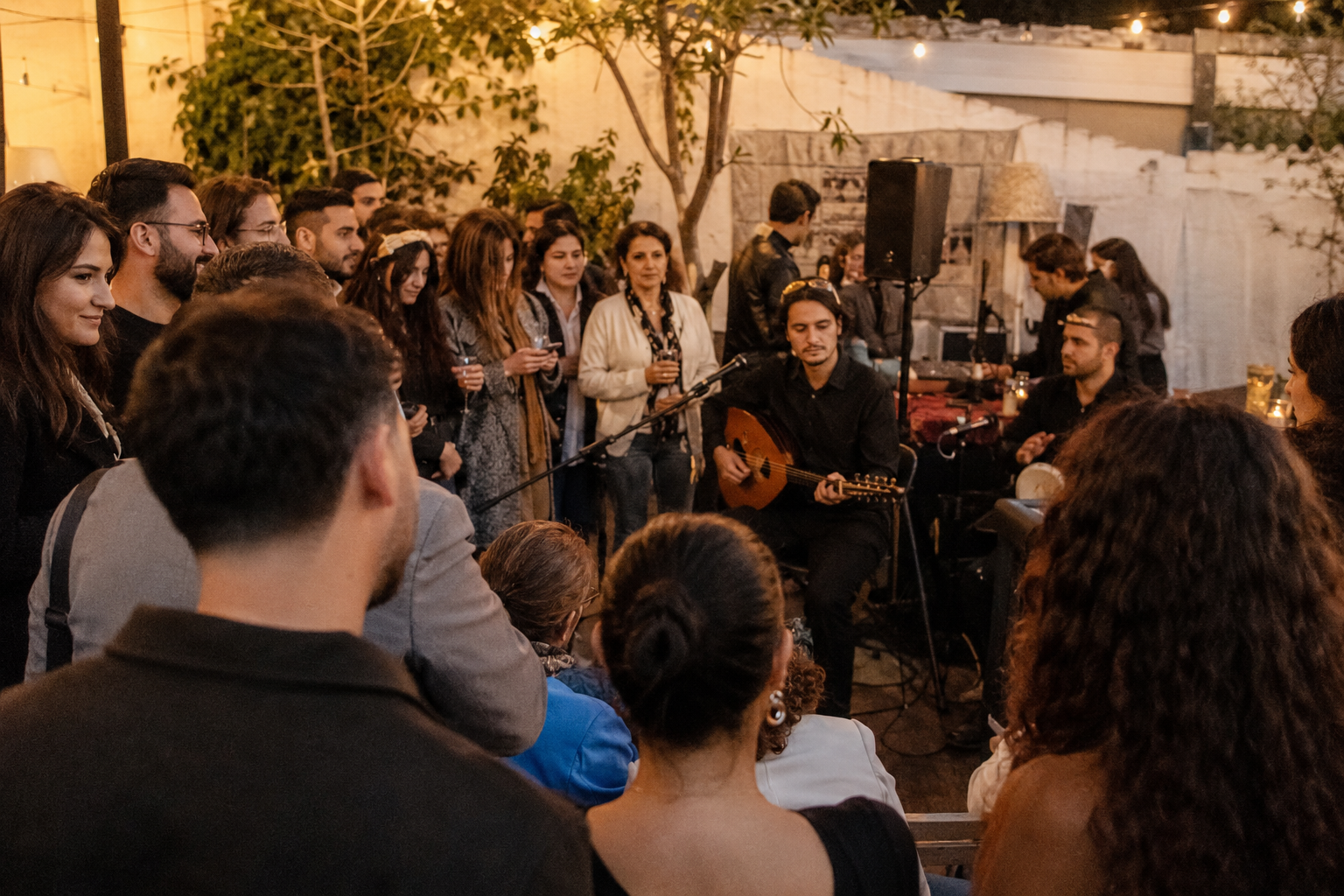 Young and older Armenian guests gathered around a live acoustic performance in a Los Angeles courtyard.
