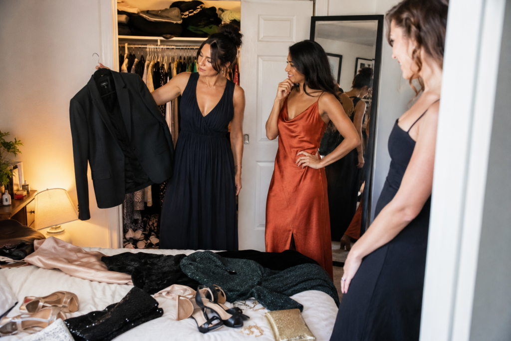 Three friends comparing formal outfits while getting ready for an event in an apartment.
